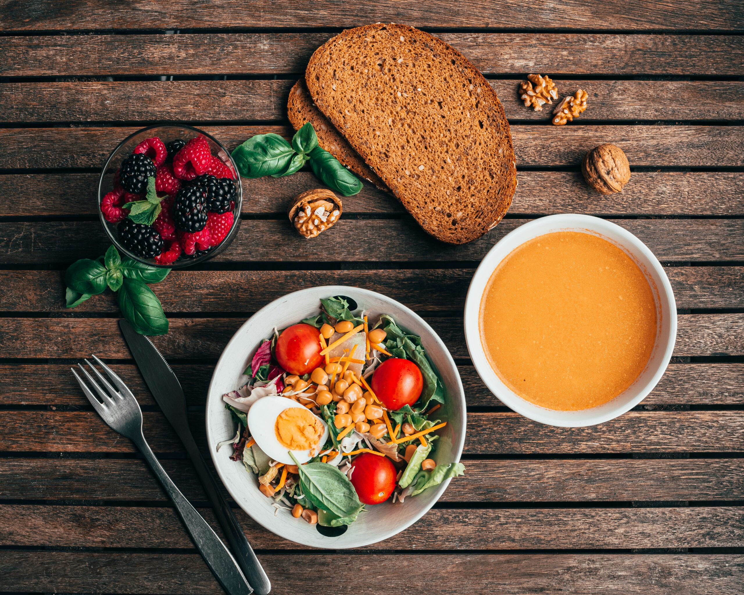 foods that cause bloating and what to eat instead - healthy anti-bloating foods on wooden table with vegetables and fruits -